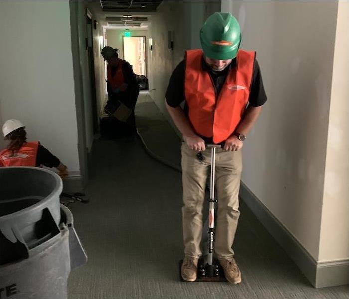 SERVPRO tech using water removal equipment in office
