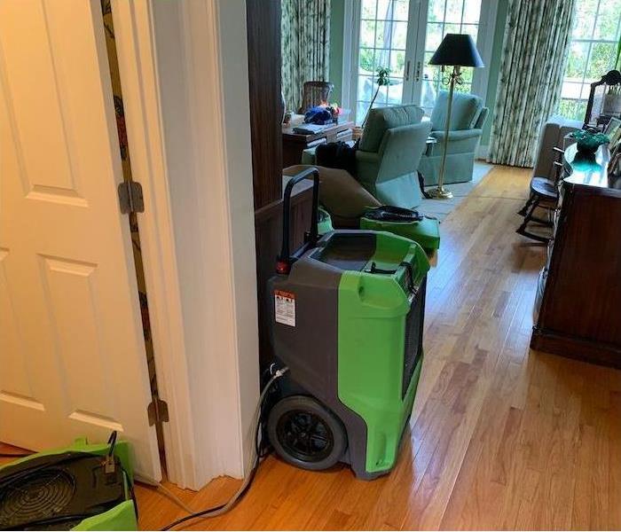 SERVPRO equipment in a hallway and a living room on hardwood floor. 
