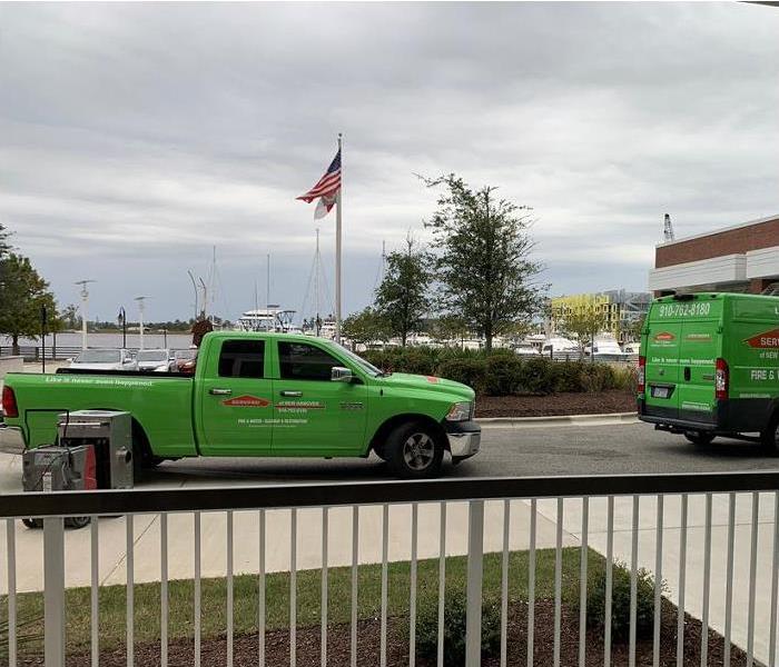 SERVPRO restoration vehicles in front of building; boats and water in background